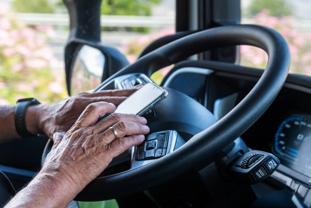 Truck driver using a smartphone while driving on a Pennsylvania highway, illustrating distracted driving liability.