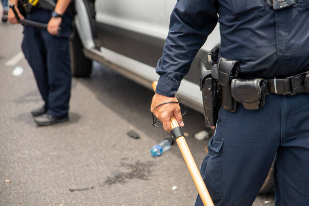 A Philadelphia police officer holding a wooden baton, representing critical physical evidence in a misconduct case.