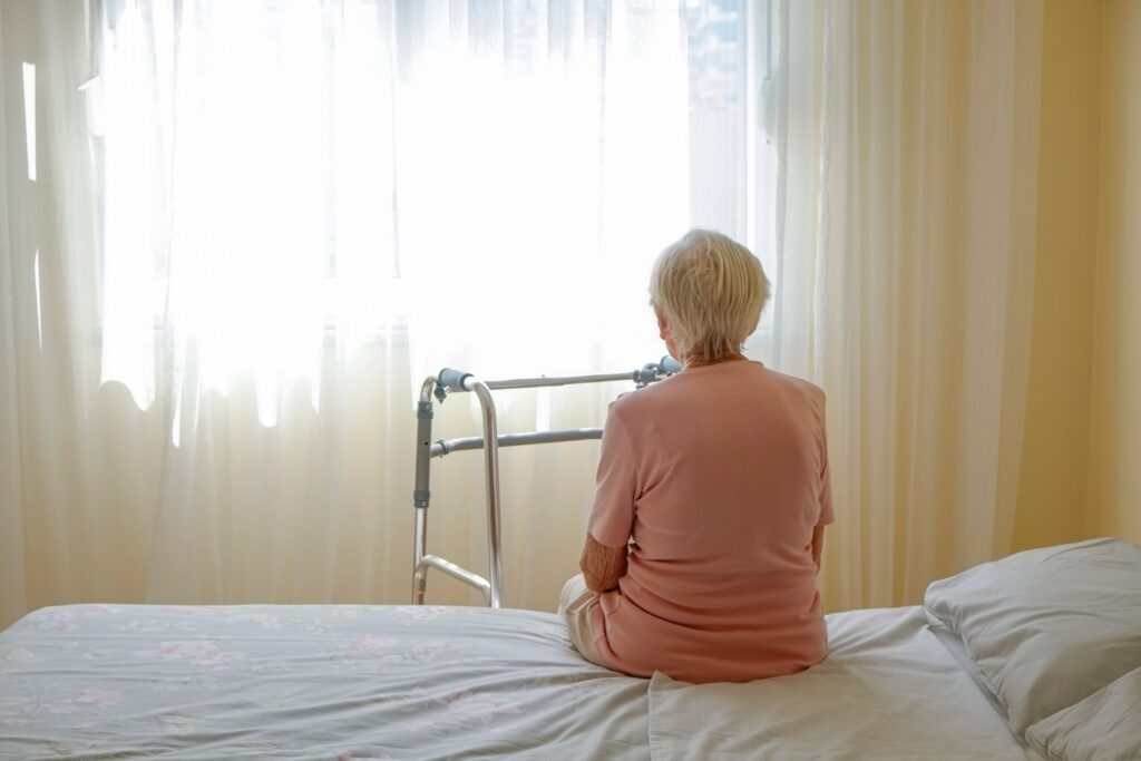An elderly resident sitting alone in a Pennsylvania care facility, illustrating potential emotional mistreatment or social withdrawal.