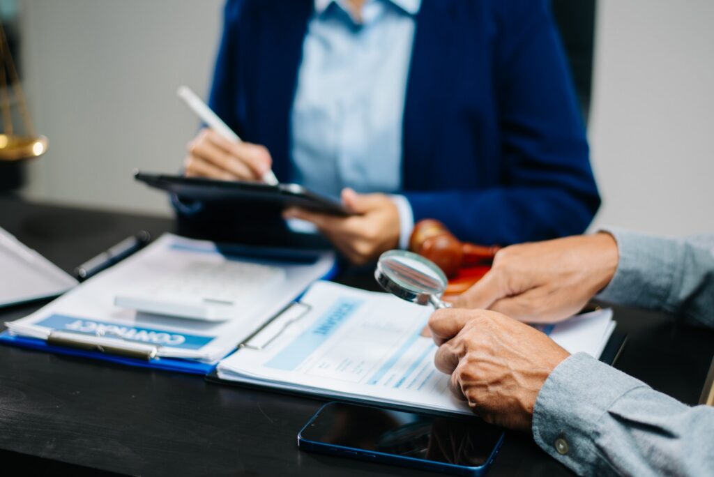 A legal professional in Pennsylvania reviewing corporate documents with a magnifying glass to identify fraud and preserve evidence.