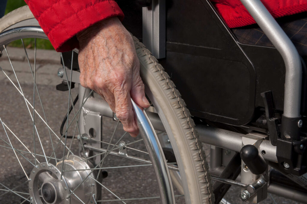 Close-up of a senior's hand on a wheelchair, highlighting the proof needed to hold Philadelphia facilities accountable for negligence.