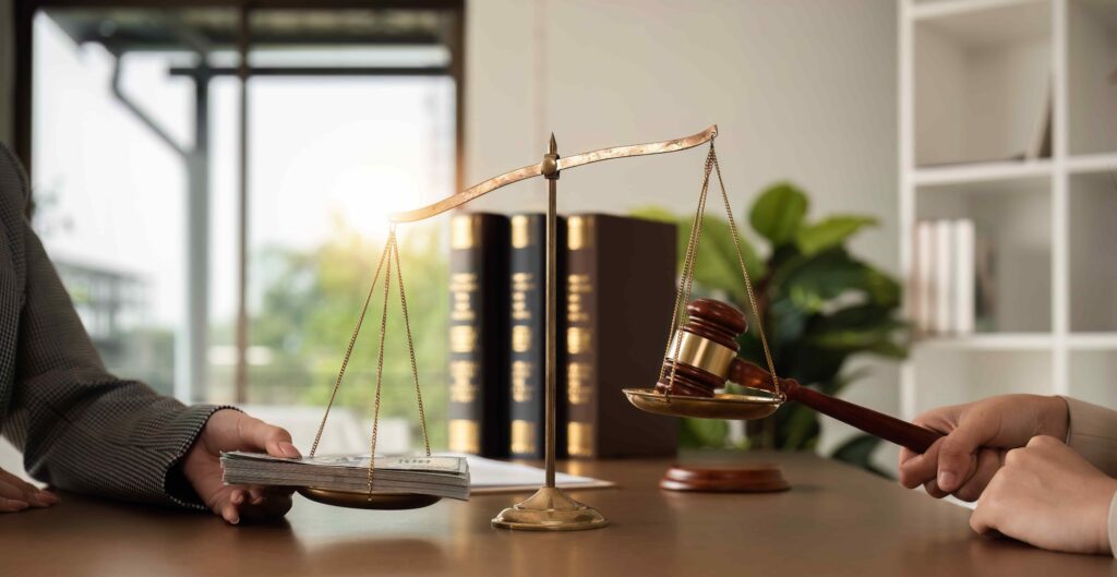 Scales of justice balancing cash and judge&rsquo;s gavel in law office.