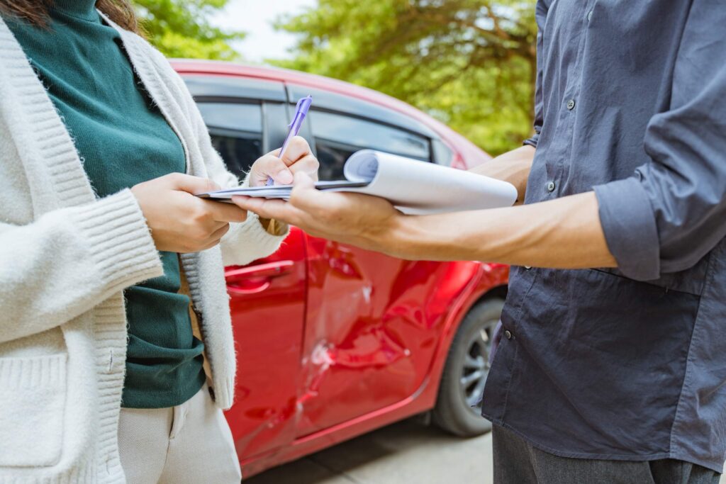 A victim reviewing a denied car accident claim in Philadelphia next to their damaged vehicle.