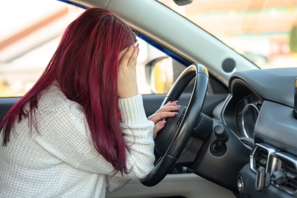 A driver experiencing delayed concussion symptoms after a car accident, a common scenario used to explain the gap in treatment defense in brain injury cases.