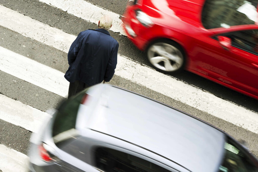 A driver yielding to foot traffic at a busy intersection, demonstrating the legal requirements handled by a Philadelphia pedestrian accident lawyer.